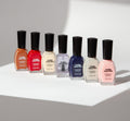 Set of six nail polish bottles with black caps on a light gray background