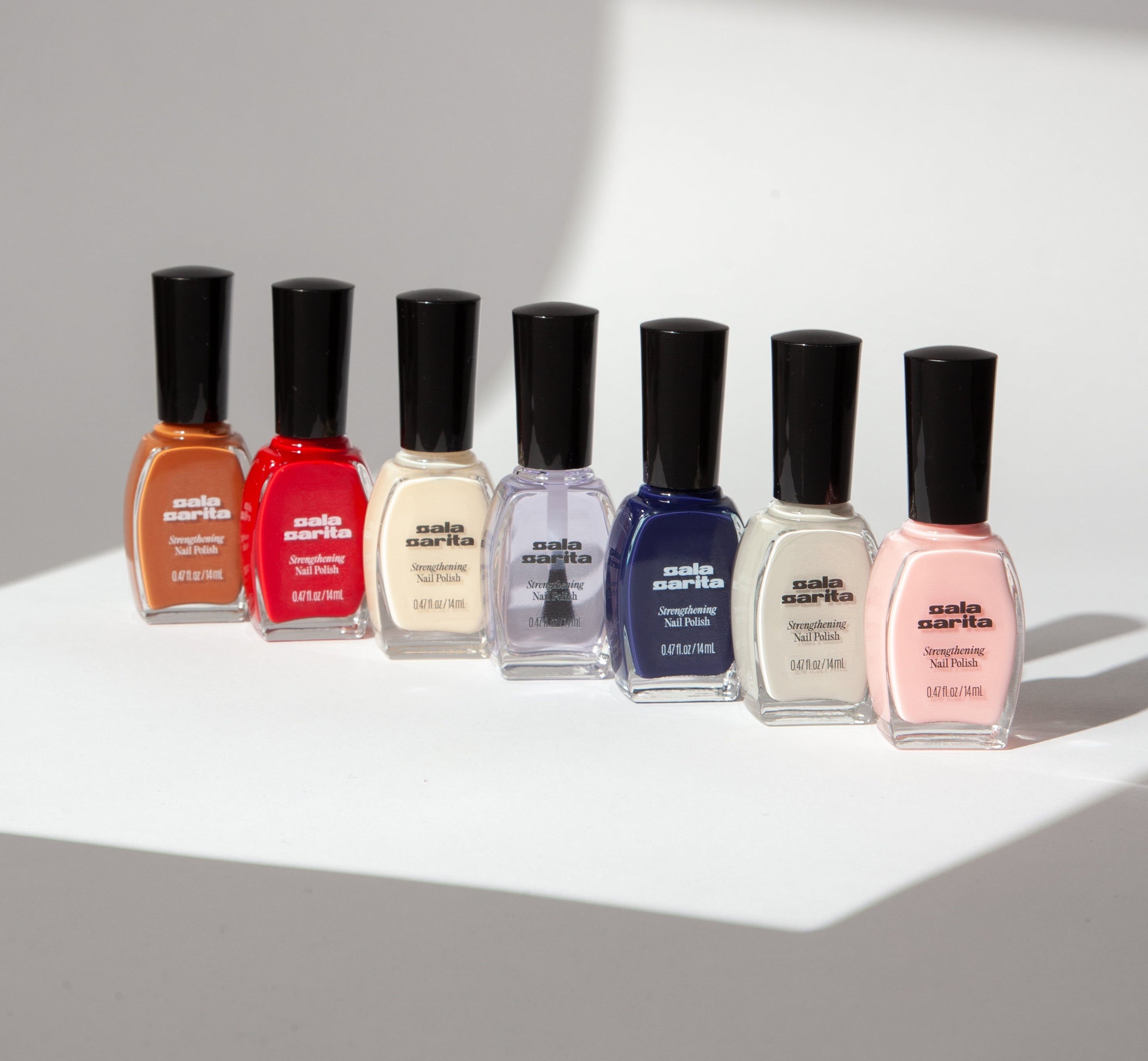 Set of six nail polish bottles with black caps on a light gray background
